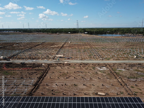 Aerial view of solar power plant under construction on a dirt field. Assembling of electric panels for producing clean ecologic energy. Alternative power concept for sutainable development. photo