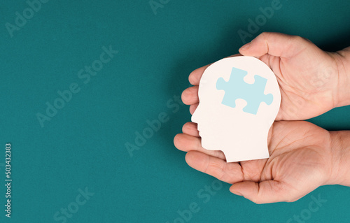 Holding a head with a puzzle piece, mental disease like Autism, Alzheimer, stroke awareness, brainstorming for ideas, memory problems
