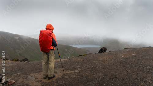 Hiking Tama Lakes track. Man looking at lower Tama lake in the mist. Tongariro National Park. photo