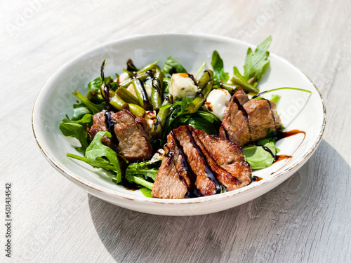 Foto Beef roasted meat with balsamic vinegar, green beans, and arugula on a white plate