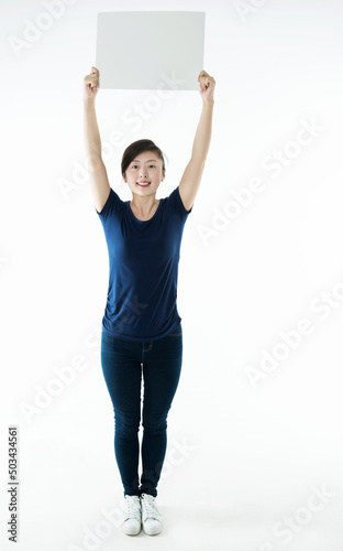 Full length young woman holding blank cardboard isolated on white background