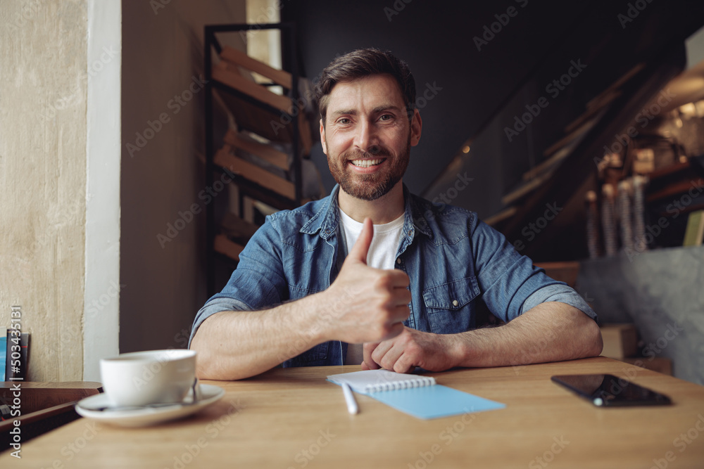 Cheerful man smiling and giving the thumbs up. Gesture of approval. Great or good coffee. Estimation Cheerful man smiling and giving the thumbs up. Gesture of approval. Great or good coffee. Estimation