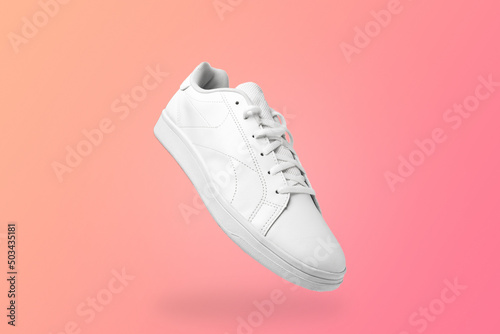 High angle view of white sneaker isolated on peachy background. Sportive pair of shoes for mockup. Fashionable stylish sports casual shoes.