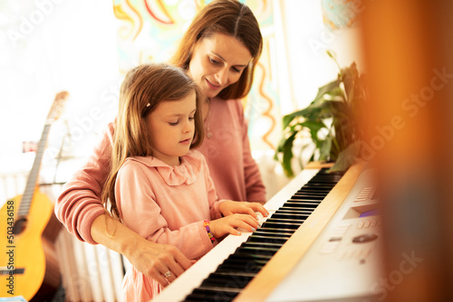 Woman and girl playing a piano. Beautiful woman teaching a little girl playing a piano..
