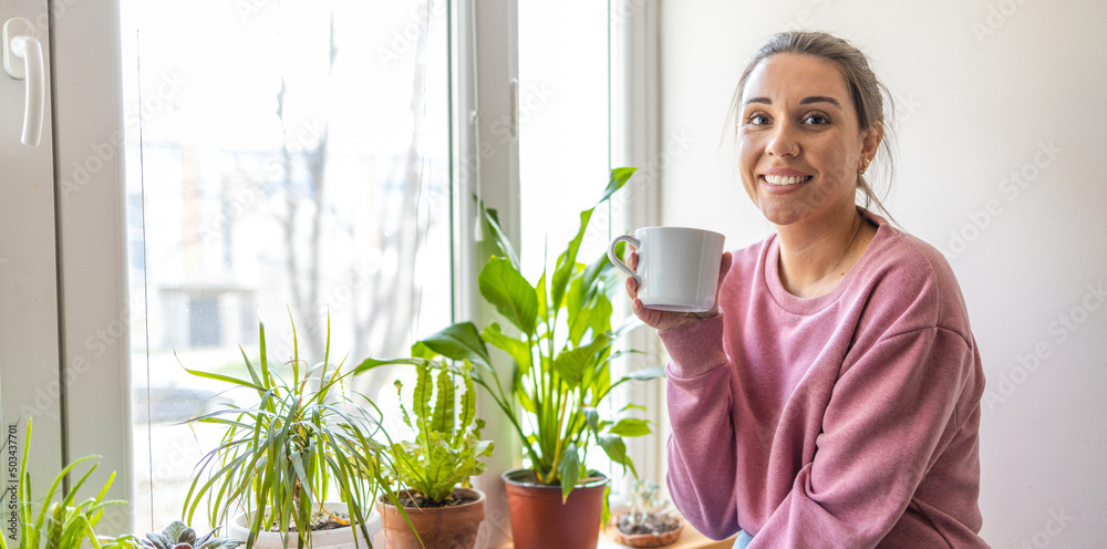 Smiling woman sitting by window enjoying coffee Smiling woman sitting by window enjoying coffee