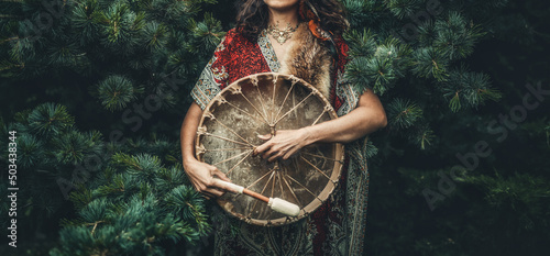 Foto shamanic girl playing on shaman frame drum in the nature.