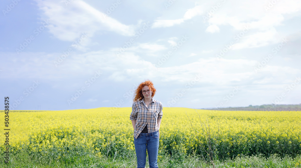 A woman in a country outfit standing in a yellow field on sunny summer day