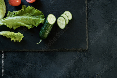 Cucumber and salad leaves on dark slate texture photo