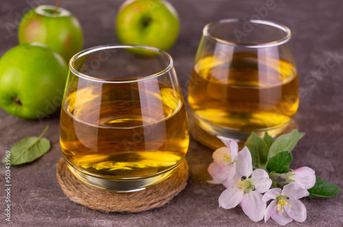 Two glasses with fresh apple juice on a gray background. 