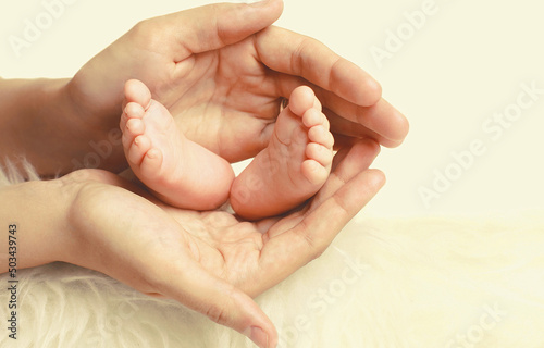 Mother holding in her hands baby feet close up