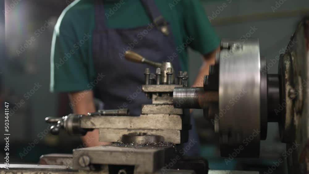 4K 50fps, Close-up of a lathe, working under the supervision of a senior mechanic, standing close to the lathe, inside his small family-owned factory. 4K 50fps, Close-up of a lathe, working under the supervision of a senior mechanic, standing close to the lathe, inside his small family-owned factory.