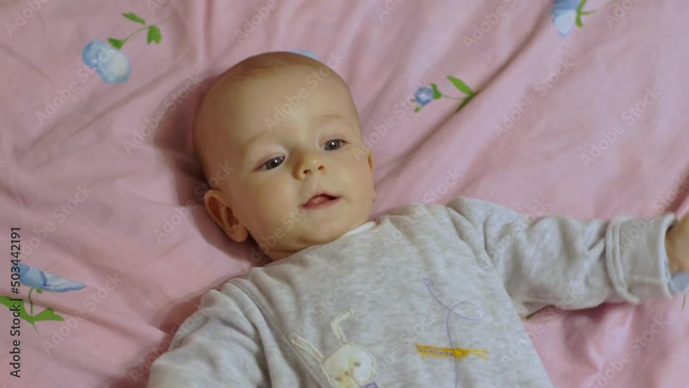 A cute baby lies on his back, smiling cheerfully and waving his arms. A cute baby lies on his back, smiling cheerfully and waving his arms.