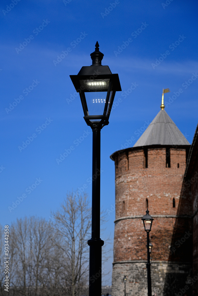 The tower of an ancient castle-fortress. Round watchtower made of brick with a wooden roof. Historical buildings. The wall of the ancient city.