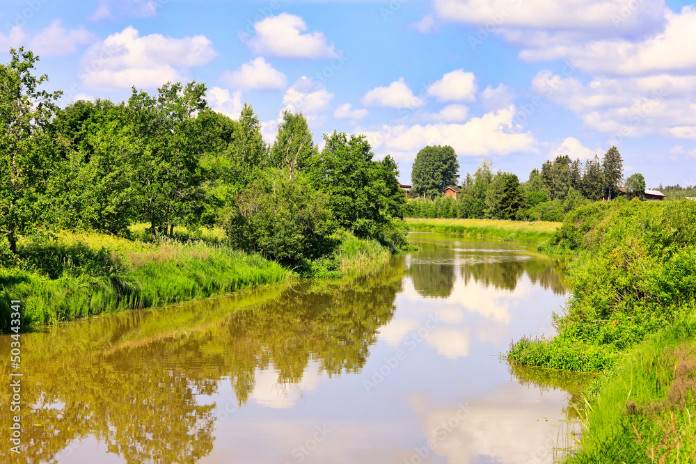 Blue sky and fairweather clouds reflected on the calm surface of a rural lake. Near Somero, Finland. 