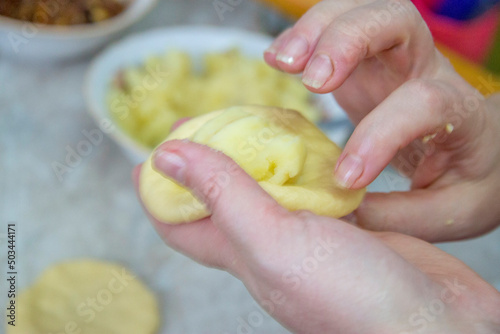 Woman stuffs pies with potatoes and onion in the kitchen