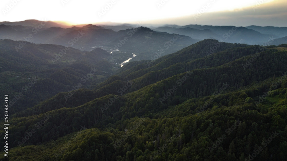 Sunset over Carpathian mountains covered with pine trees in Ukraine captured in an aerial drone shot