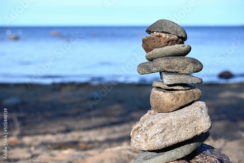 Piles of gray stones are stacked in a Zen pyramid on the Baltic Sea coast for close-up meditation. Rest, meditation, tranquility, balance on the beach of the sea in summer.  photo