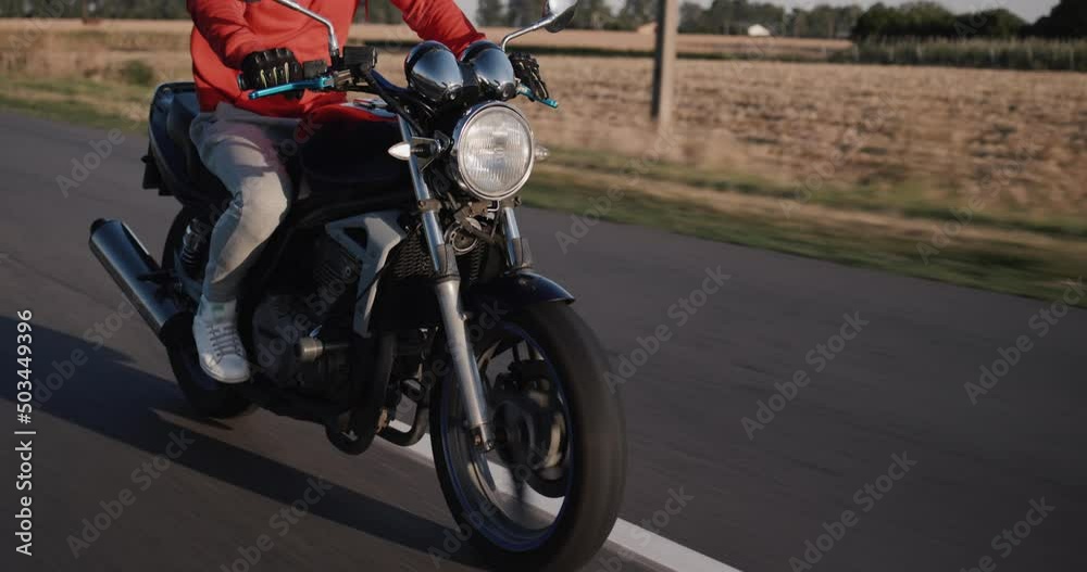 A motorcyclist rides along a rural road along corn fields. A motorcyclist rides along a rural road along corn fields.