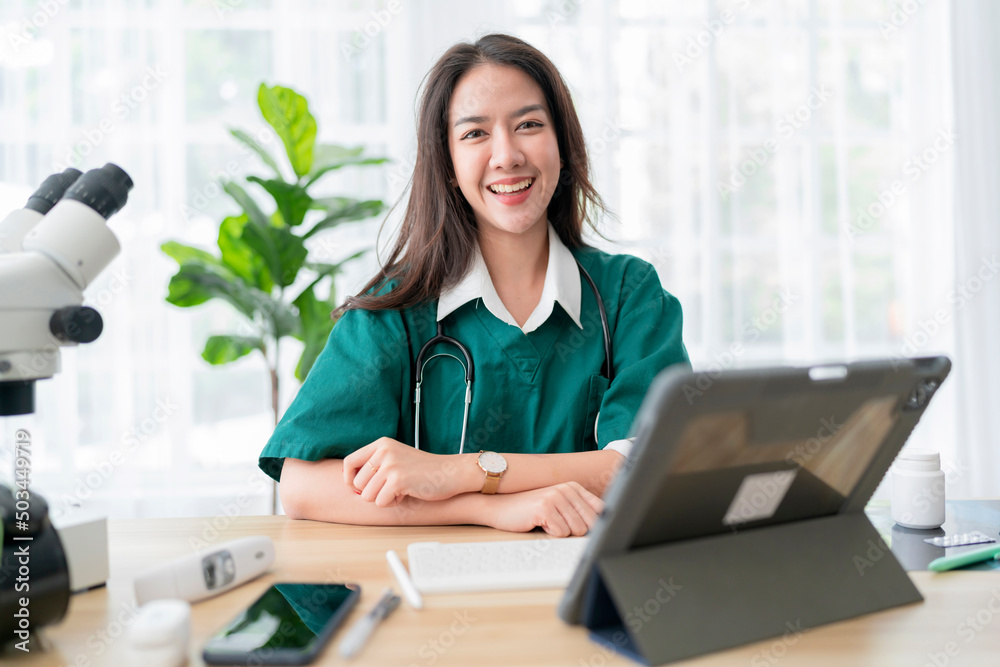 Young attractive Asian female doctor diagnosis talking and looking to camera in video conference ,Positive doctor waving and having online consultation on digital tablet laptop Young attractive Asian female doctor diagnosis talking and looking to camera in video conference ,Positive doctor waving and having online consultation on digital tablet laptop