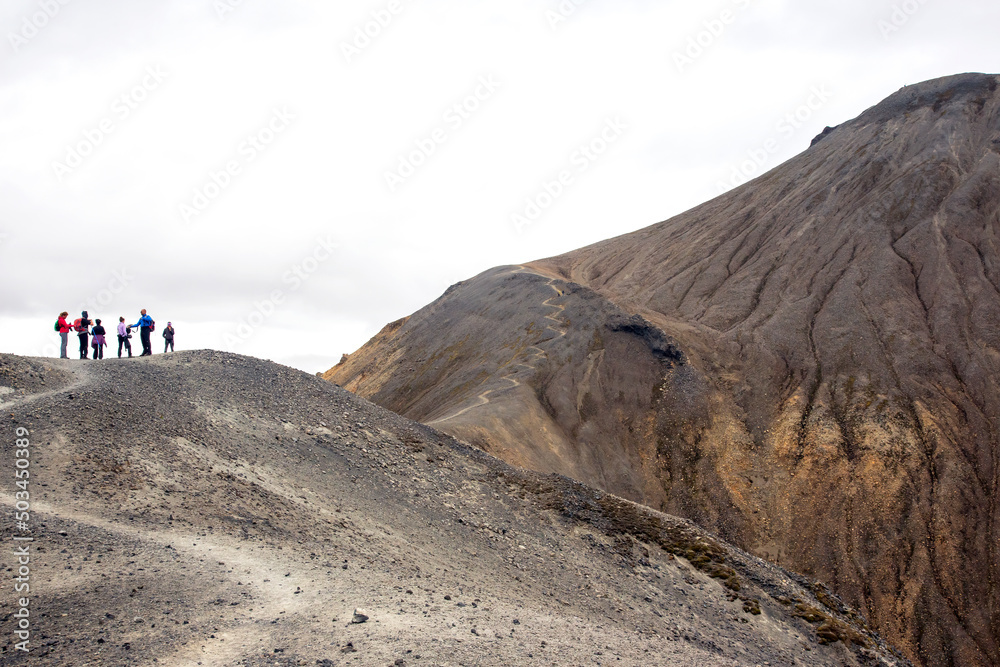 Tourists climb the trail to the top of the volcano. Volcanic lava near the volcano in Landmannalaugar. Iceland
