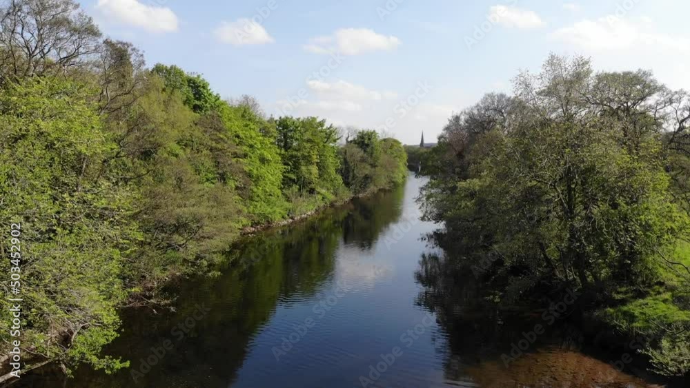 Cinematic descent through tree lined blue river stream next to forest. Ancient woodland area in Yorkshire Dales Cinematic descent through tree lined blue river stream next to forest. Ancient woodland area in Yorkshire Dales