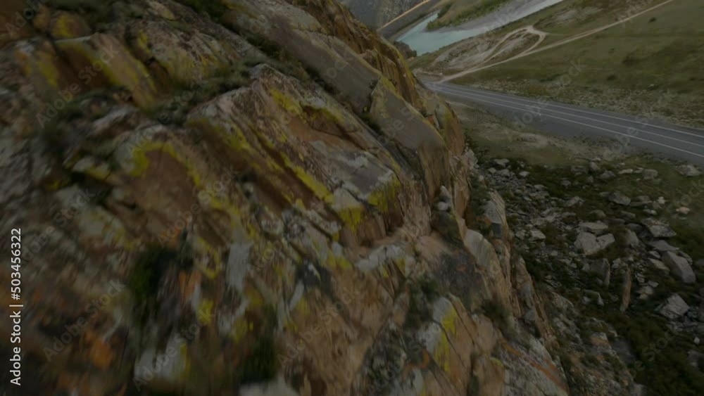 FPV sport drone flying near cliff cracked texture minibus riding on asphalt highway nature environment. Aerial view rocky terrain majestic high top mountain travel tourism journey transportation in 4k FPV sport drone flying near cliff cracked texture minibus riding on asphalt highway nature environment. Aerial view rocky terrain majestic high top mountain travel tourism journey transportation in 4k