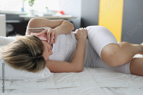 Young woman stay at home, belly hurts, suffering menstrual period pain photo