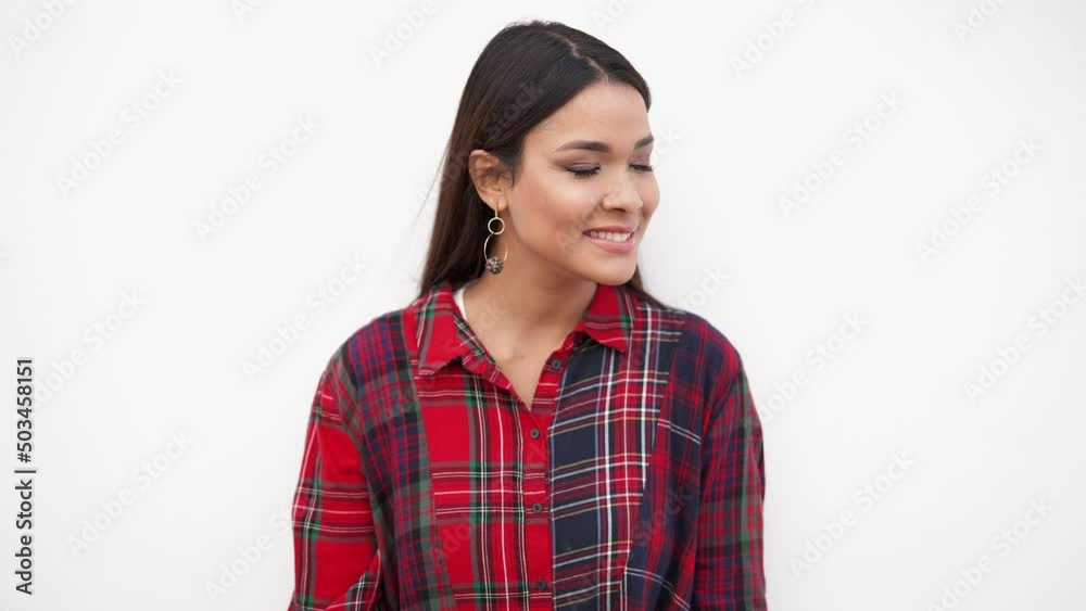 Young woman in trendy outfit standing near white wall and looking at camera Young woman in trendy outfit standing near white wall and looking at camera