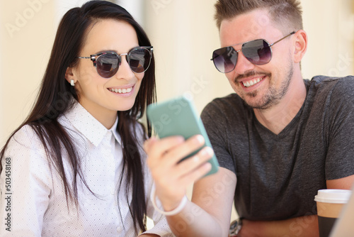Couple watch memorable pictures on smartphone  go through pics from holiday