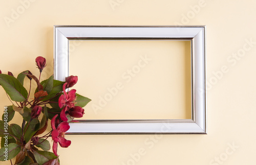 Beautiful flower arrangement. A branch of red flowers, an empty photo frame for text on a light pastel background. Wedding. birthday. Valentine's Day, Mother's Day. Top view, copy space