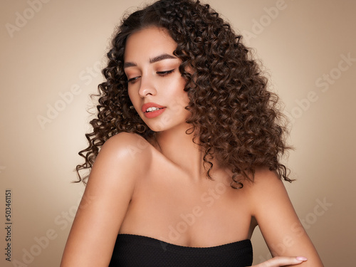 Fashion studio portrait of beautiful smiling woman with afro curls hairstyle. Fashion and beauty