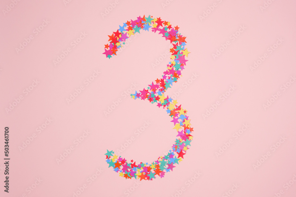Number 3 or three made from decorative multi-colored stars. Holiday numbers or figures. Top view Number 3 or three made from decorative multi-colored stars. Holiday numbers or figures. Top view
