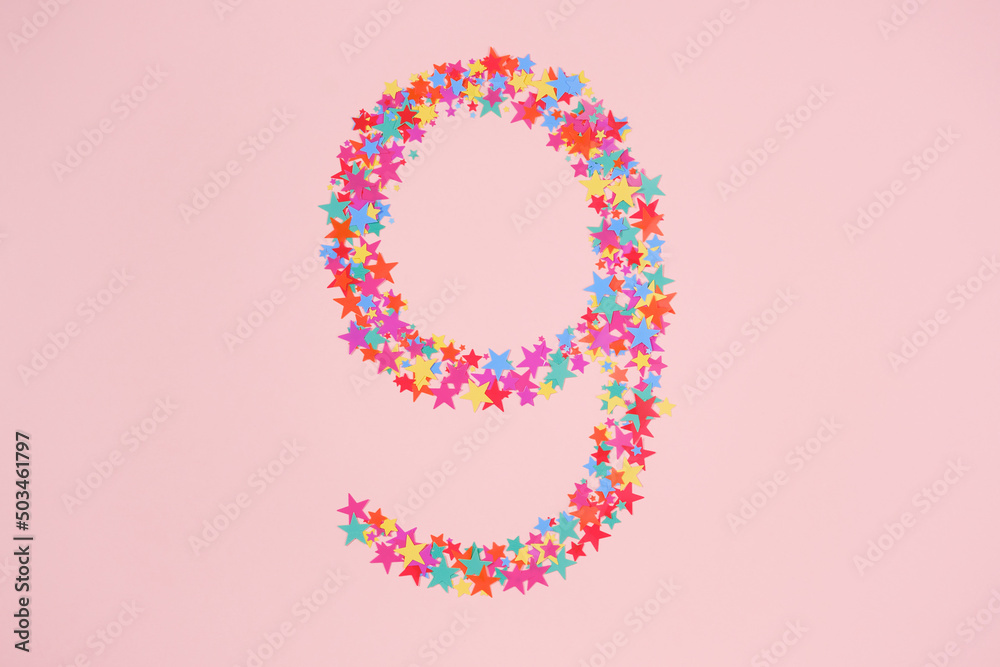 Number 9 or nine made from decorative multi-colored stars. Holiday numbers or figures. Top view Number 9 or nine made from decorative multi-colored stars. Holiday numbers or figures. Top view