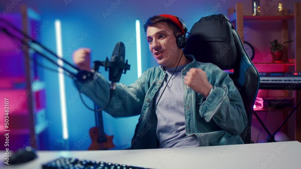 Young hipster man playing online computer video game, colorful lighting broadcast streaming live home. Ecstatic celebration winning match. Gamer lifestyle, E-Sport online gaming technology concept Young hipster man playing online computer video game, colorful lighting broadcast streaming live home. Ecstatic celebration winning match. Gamer lifestyle, E-Sport online gaming technology concept