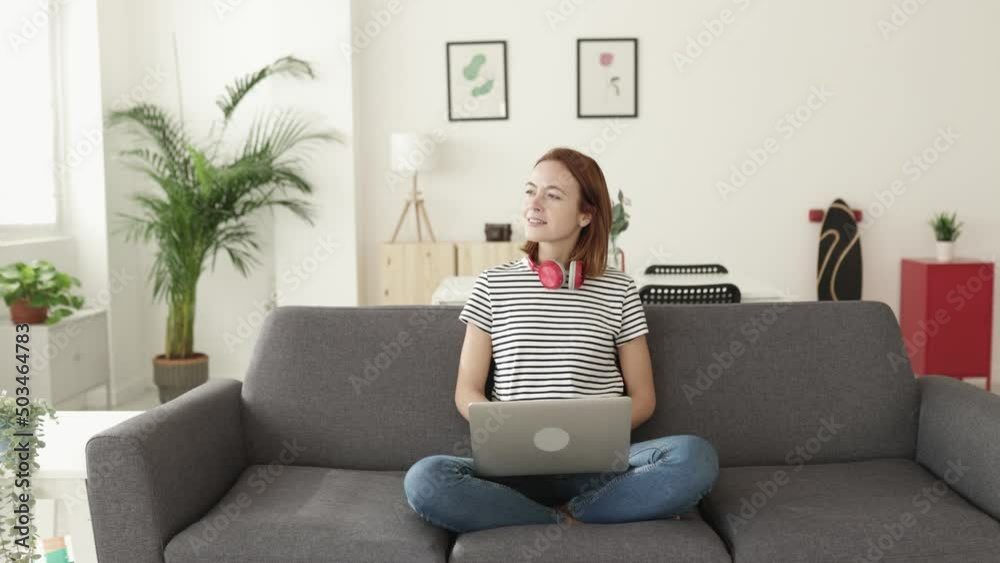Young woman using laptop computer sitting on sofa at home. High quality 4k footage Young woman using laptop computer sitting on sofa at home. High quality 4k footage