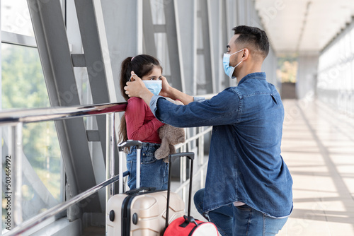 Caring Arab Father Wearing Protective Medical Mask To His Daughter At Airport