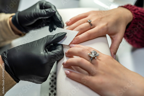manicurist makes the client preparatory procedures for applying varnish in a beauty salon