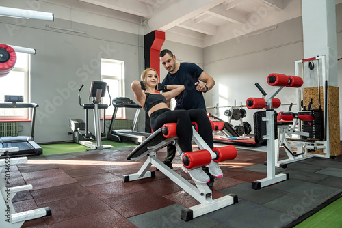 personal male trainer working with young slim woman client in gym