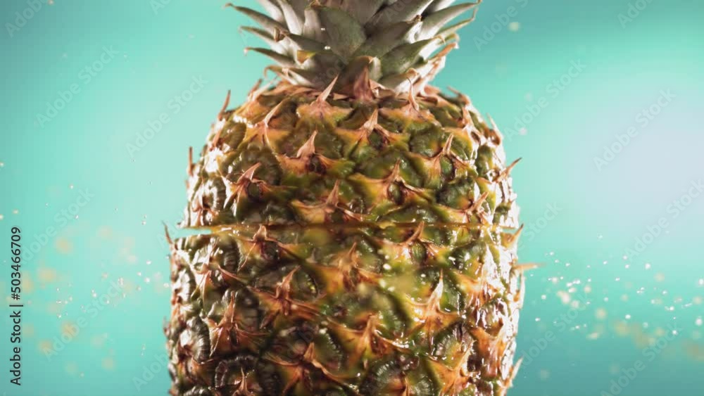 Half Pineapple falling and splashing on turquoise background. Food levitation concept. Slow Motion