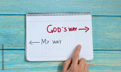 Stampa su tela God's way, message quote on a notebook with a hand showing in direction to handwritten arrow isolated on a light blue wooden background