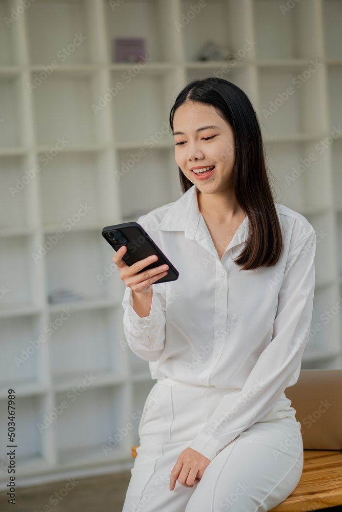 Beautiful Asian woman standing and chatting with friends on mobile phone typing messages on the Internet. Communication concept, close-up