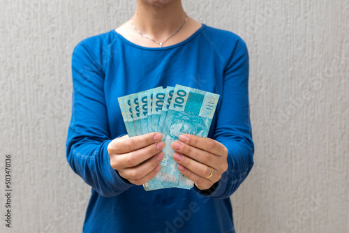 woman holding brazilian money. economy and inflation concept