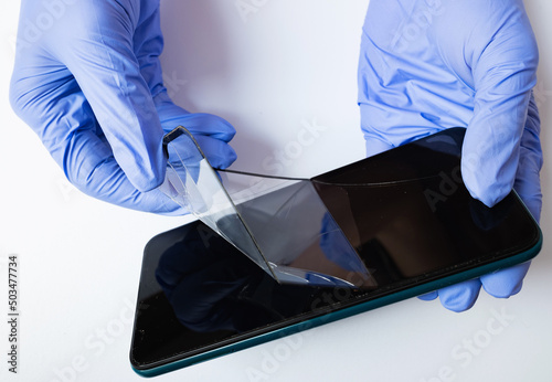 Картината върху платно Person's hands holds broken and cracked smartphone screen protective covering glass