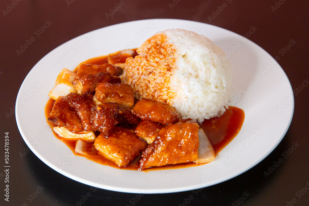Sweet and sour fish on rice of traditional Cantonese yum-cha Asian gourmet cuisine meal food dish on the white serving plate and brown red table