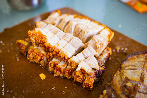 Traditional Cantonese yum-cha roast pork BBQ Asian gourmet cuisine with crispy golden pork skin on the chopping board