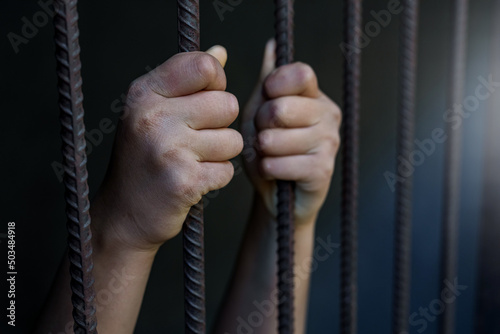 Hands holding a steel cage in old iron bar. Restriction of the rights of human. © AungMyo