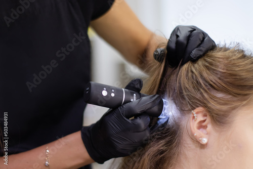 Trichology. Doctor diagnoses the structure of the hair. Consultation with a trichologist. Modern optical diagnostic equipment in dermatology and trichology clinic