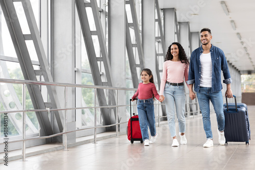 Travel Advertisement. Portrait Of Happy Arab Family Walking With Luggage At Airport