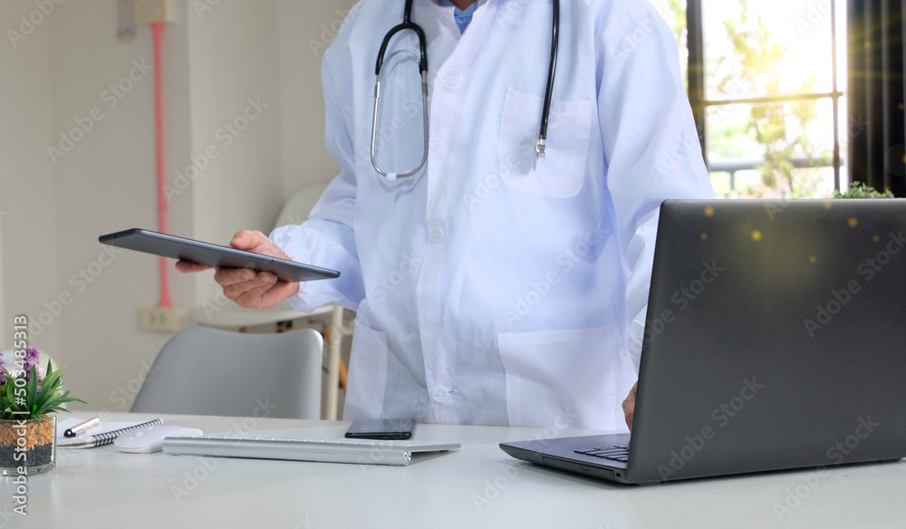 Doctor working on a laptop at his clinic is shown in close-up. A young doctor is hard at work. Outstanding medical service and medical idea Doctor working on a laptop at his clinic is shown in close-up. A young doctor is hard at work. Outstanding medical service and medical idea