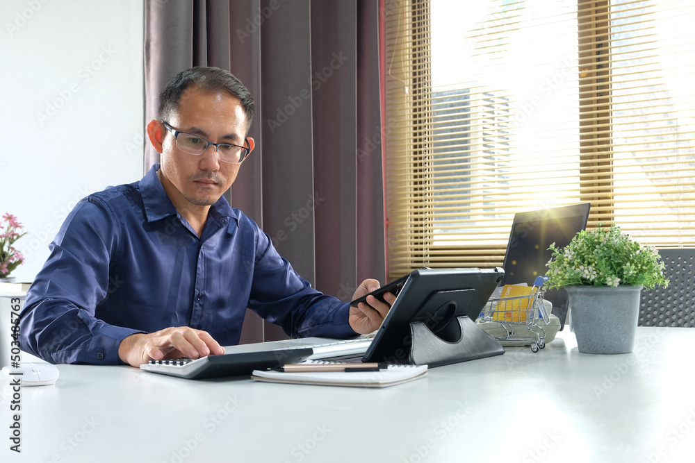 Businessman using smart phone and laptop at office. Businessman or student working on computer and texting smartphone. Freelance, education and technology concept Businessman using smart phone and laptop at office. Businessman or student working on computer and texting smartphone. Freelance, education and technology concept